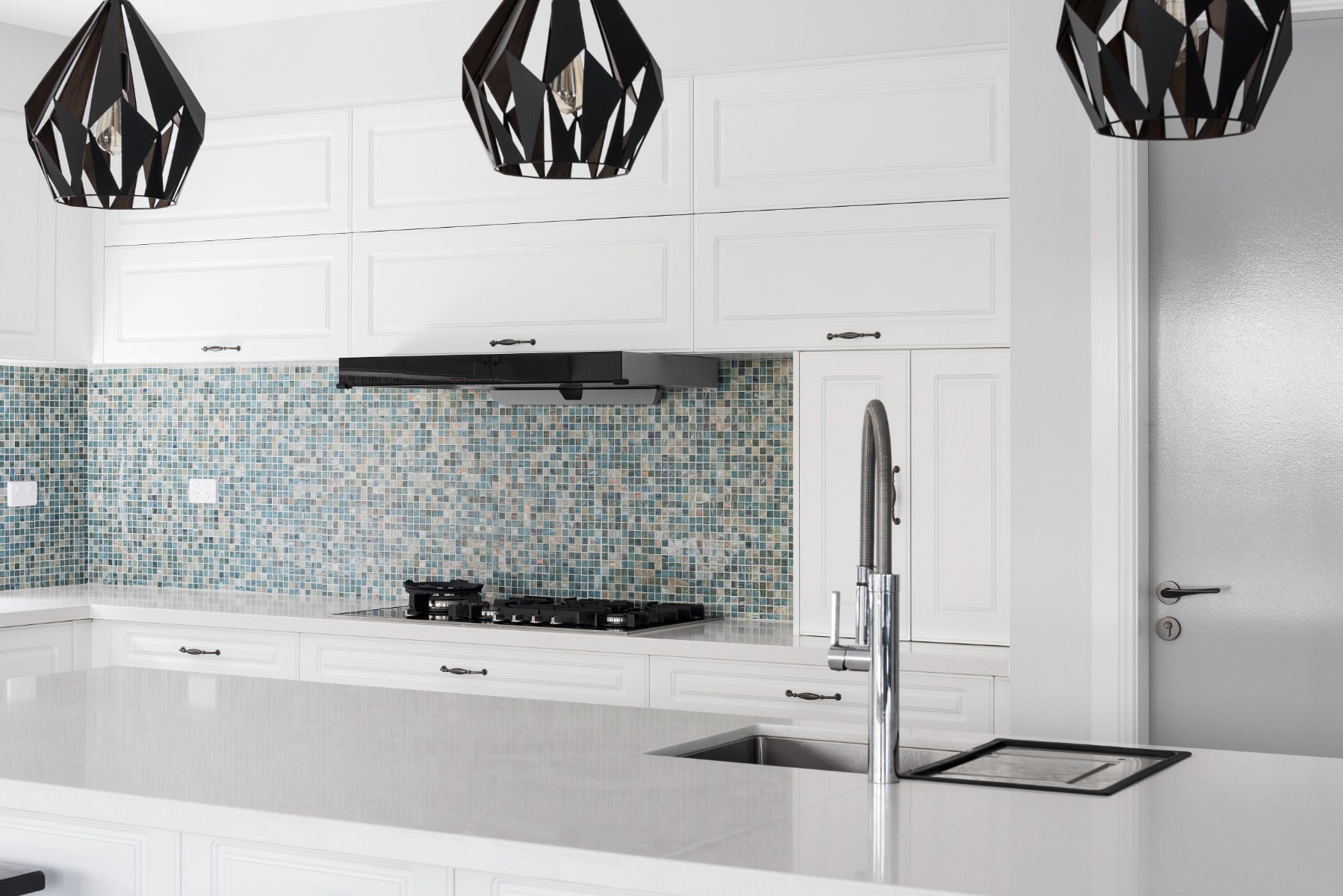 A sleek kitchen splashback featuring glossy blue and green glass tiles. The smooth, polished surface of the glass adds a modern and elegant touch to the kitchen, purchased from amber